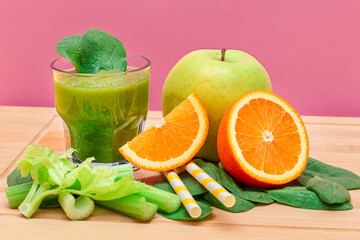 Fresh Green Smoothie of Apple, Celery, Spinach and Orange in Glass Beaker with Yellow Cocktail Straw on Wooden Cutting Board. Vegan Detox Drink. Vegetarian Culture. Healthy Eating and Fruit Diet