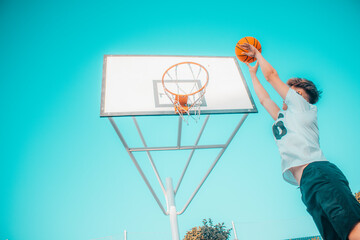 Jugador de baloncesto canastando y saltando con el balón en la pista de juego para ganar puntos