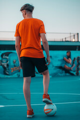Jugador de futbol jóven de espaldas en una cancha posando de pie en la pista para marcar gol en la red de la porteria  © Migue Suarez
