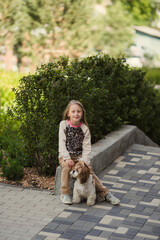 beautiful preteen girl petting and hugging shih tzu dog looking at the camera outdoors.