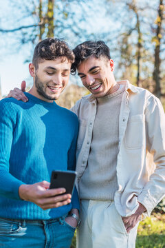 Cheerful couple of gay men watching video on smartphone
