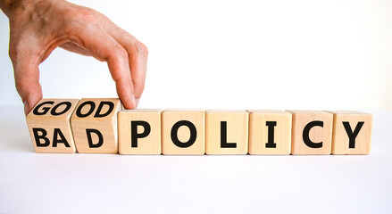 Good or bad policy symbol. Businessman turns wooden cubes and changes words 'bad policy' to 'good policy'. Beautiful white table, white background. Business, bad or good policy concept. Copy space.