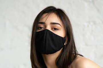 portrait of young beautiful woman in black mask in studio