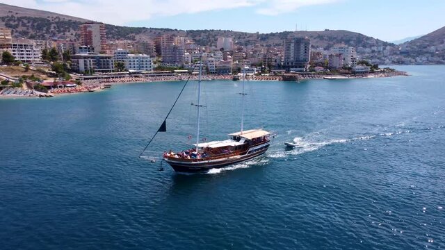 An old two-masted ship sails on the waves of the Ionian Sea against the backdrop of the city