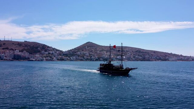 Against the background of the mountains sails an old ship with the flag of Albania