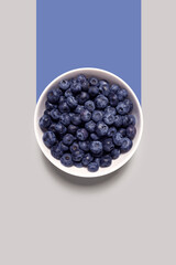 Creative food health diet concept photo of plate dish bowl with blueberry on grey background..