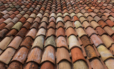 Detail of an Italian roof. Terracotta tiles of an ancient house in the province of Treviso, Italy. Orange surface illuminated by the sun.