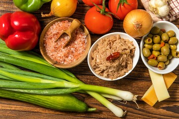 Tasty tuna salad with vegetables on wooden table. Vegetable salad with tuna. Preparing a healthy vegetable salad with fish. Diet food for athletes.