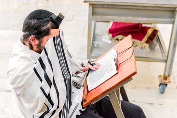 Orthodox Jewish man, with phylacteries (tefilin) and shawl (tallit), covering his eyes with his shawl during prayer.