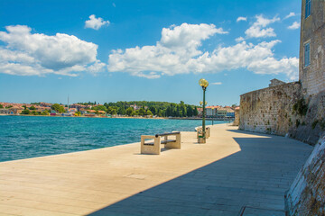 Part of the old defensive walls of the historic medieval coastal town of Porec in Istria, Croatia. The coast to the north of the town centre can be seen on the opposite shore
