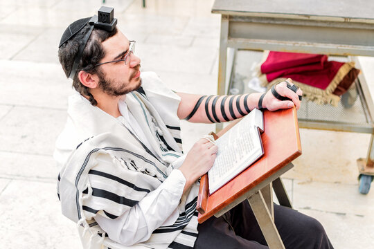Orthodox Jewish man, wearing phylacteries (tefilin) and shawl (tallit), sitting praying at the Western Wall, Jerusalem.
