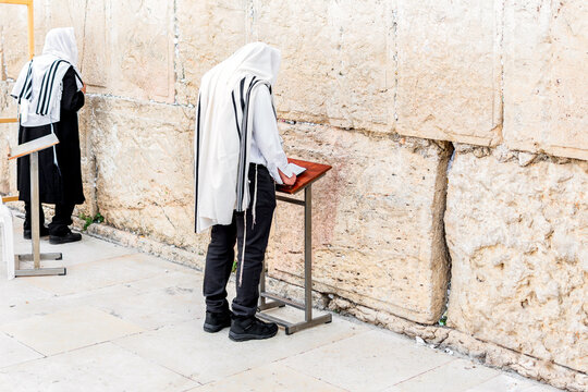 Two Orthodox Jewish men, with phylacteries (tefilin) and shawl (tallit), praying at the Western Wall in Jerusalem.