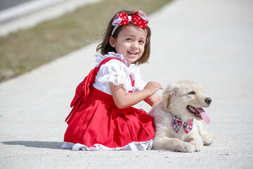 Linda criança com vestido vermelho brincando com cachorro Golden Retriever .