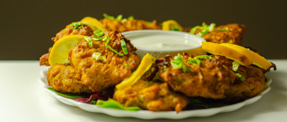 Delicious onion bhaji fritters served on ceramic plate with white dip