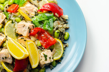 Pieces of cooked salmon and edamame soya beans with red pepper  and baby leaf spinach, served with brown long grain rice with lemon peel and ginger, soya, honey and black fungus mushroom sauce