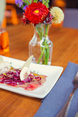Tuna carpaccio with purple cabbage and sliced parmesan cheese. Carpaccio wooden table in restaurant. Sunny lunchtime