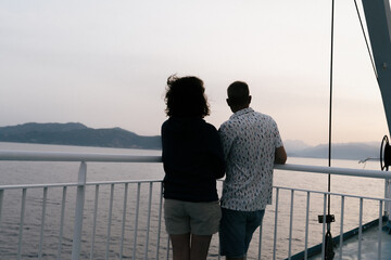 Couple face à la mer dans un bateau avec la côte visible en arrière plan