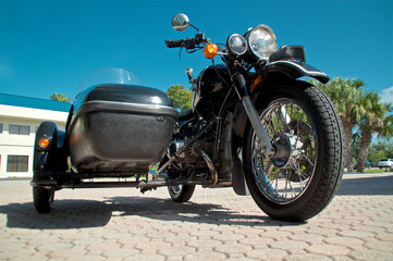 Ground level view of vintage sidecar motorcycle against blue sky.