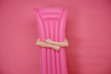 arms embracing inflatable pool stretcher on pink background