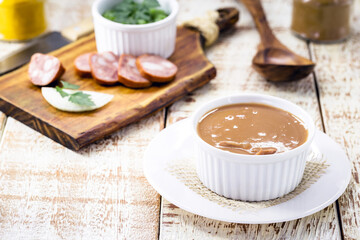 Brazilian bean broth, homemade bean soup served warm in winter, with ingredients in the background