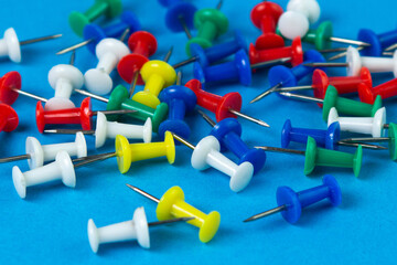 Multi-colored push pins on a blue background. Office stationery.
