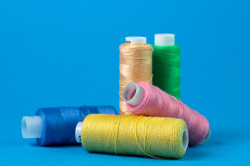 Colored spools of thread on a blue background. Sewing and needlework concept.