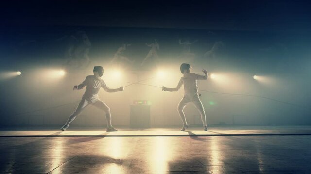 Footage of two fencing athletes duel . Two Professional Fencers Show Masterful Swordsmanship in their Foil Fight. Fencing training . Shot on ARRI ALEXA camera . 