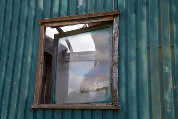 broken window on an old construction trailer, roof of the trailer is broken as well