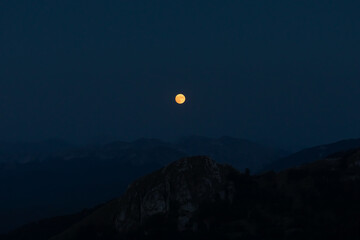 Full red moon. Splendid full red moon rises over the mountain ridges of the Apennines.