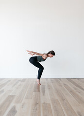 woman practicing yoga on tiptoes in gym exercising flexible 