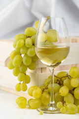 Glass of white wine and grape cluster.