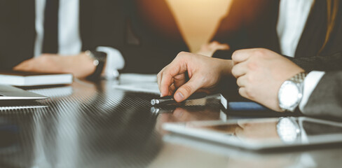 Unknown businessmen and woman sitting, working and discussing questions at meeting in sunny office, close-up. Success concept