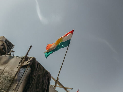 Kurdish flag flying against grey blue sky