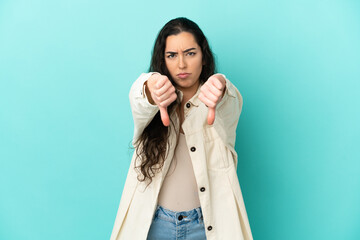 Young caucasian woman isolated on blue background showing thumb down with two hands