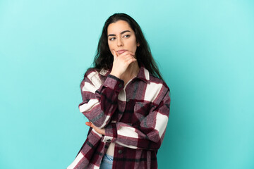 Young caucasian woman isolated on blue background having doubts