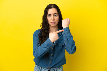 Young caucasian woman isolated on yellow background making the gesture of being late