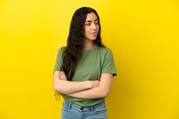 Young caucasian woman isolated on yellow background keeping the arms crossed