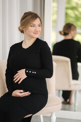 Beautiful pregnant woman sitting on chair at home. Woman waiting for baby