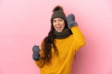 Young caucasian girl with winter hat isolated on purple background celebrating a victory