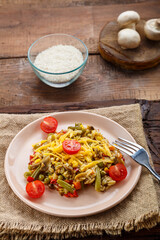 Risotto with mushrooms in a plate on a wooden background on a linen napkin and a fork and ingredients.