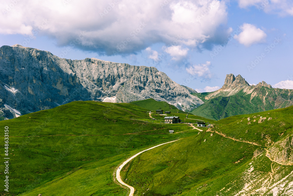 Wall mural Alpine huts located between the mountains on lush green fields of grass in the Dolomite mountains