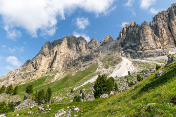 Fototapeta na wymiar Dramatic rocky mountain peaks rising out of the green hills in the Dolomite mountains