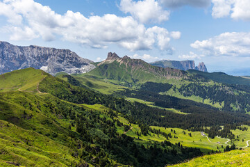 Jagged mountain ranges rising over the lush green fields of grass in the Dolomite mountains