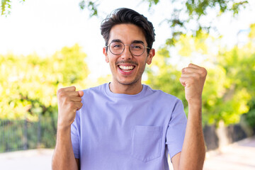 Young caucasian man at outdoors in a park celebrating a victory in winner position