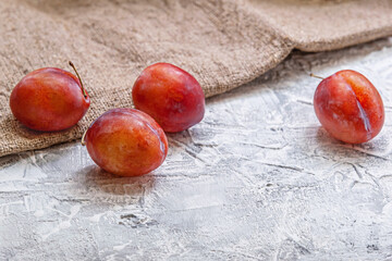 sweet ripe red plums on a rough surface