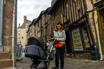 Fototapeta na wymiar A young mother in the medieval half-timbered houses in Rennes. Capital of the province of Brittany, France