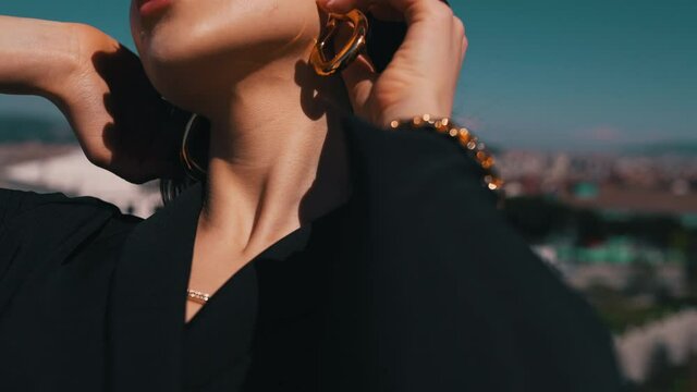 girl demonstrates earrings on the background of the city