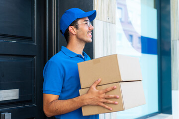 Young delivery man at outdoors holding boxes with happy expression