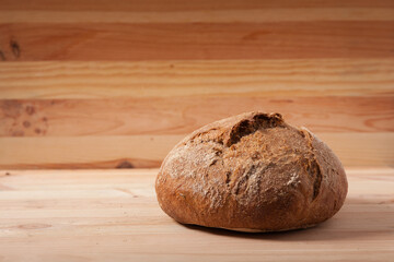Handmade fresh wheat bread on wooden background in the morning light. horizontal frame side view with space area for text or design