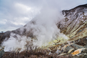 Clouds of hot thermal steam geysers in active volcano in Owakudani Valley. Located in Fuji Hakone Izu National Park, Japan.